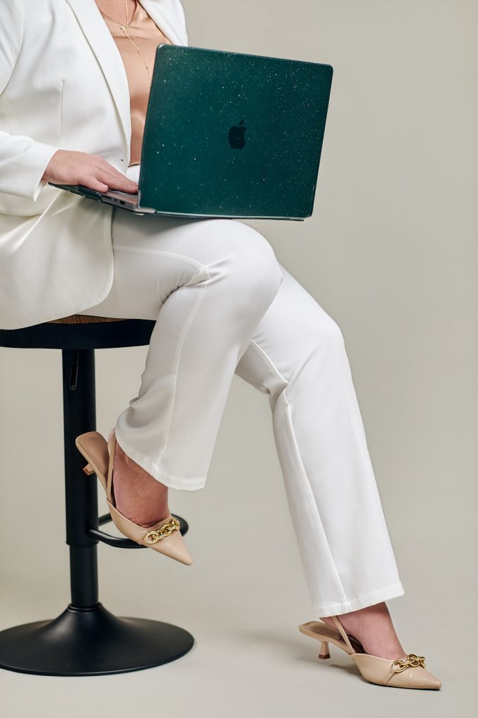 Cropped lifestyle brand photo of a woman in a white suit working on a laptop