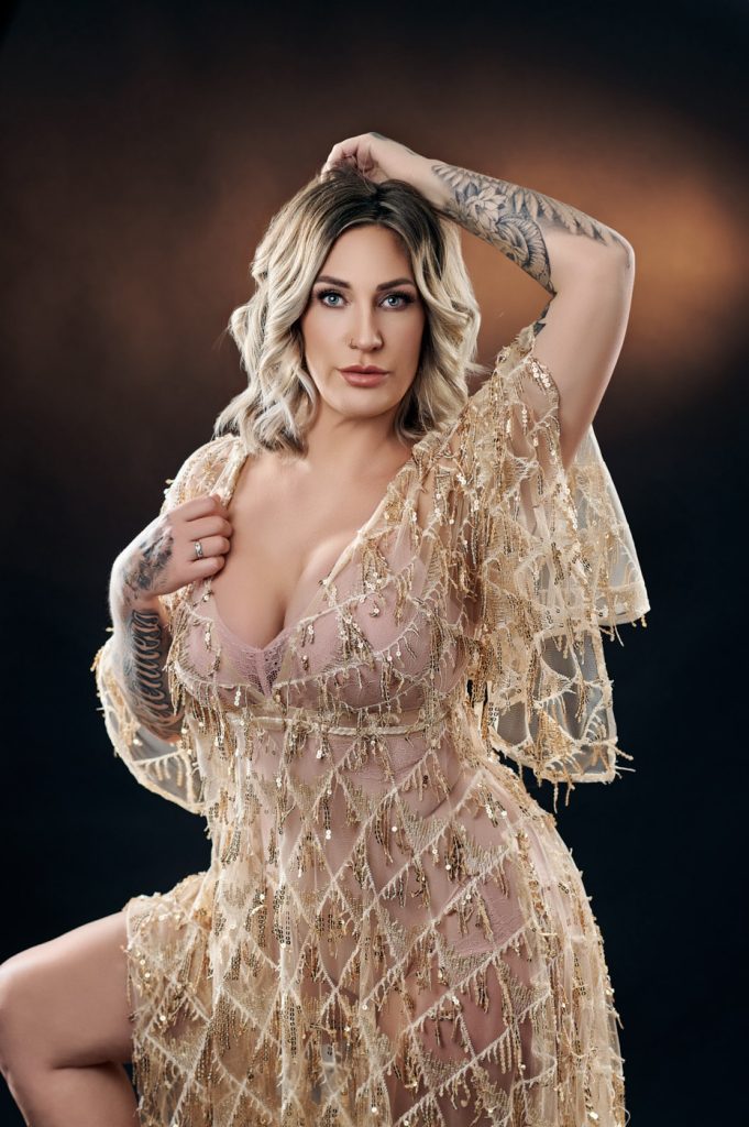 Editorial glamour portrait of a tattooed woman in a gold dress, studio photography near Ocala