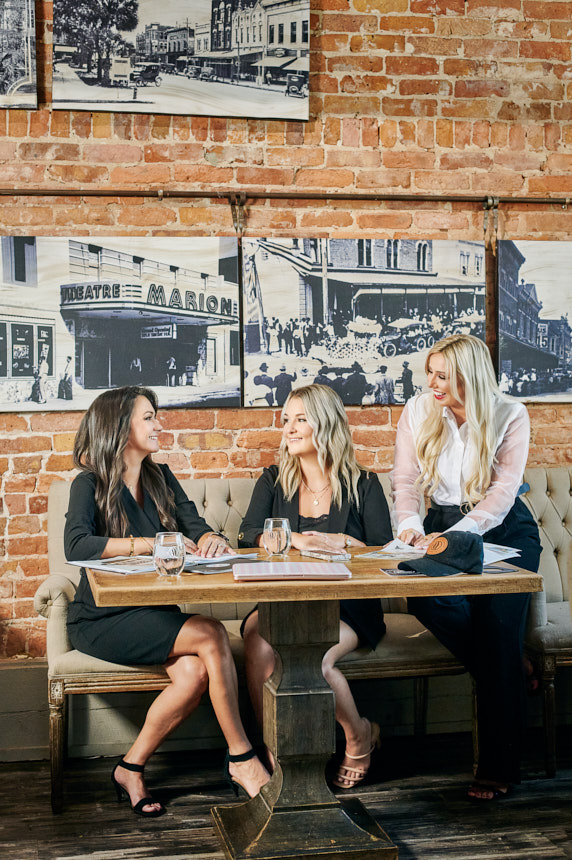 Ashley Yates Realty team reviewing marketing materials at Ivy on the Square during an Ocala real estate brand photography session